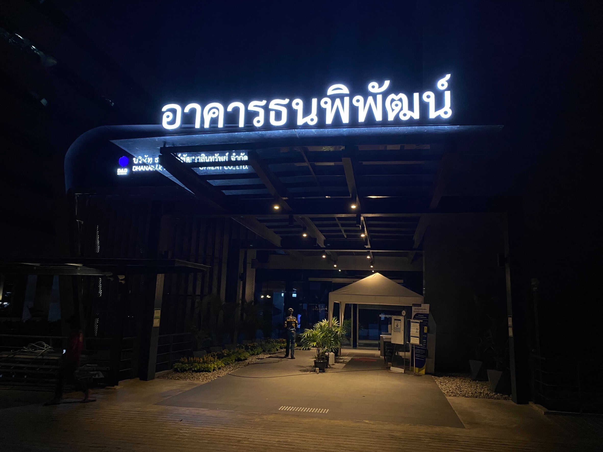 ป้ายนีออนสีขาวสว่างติดตั้งหน้าอาคารธนพิพัฒน์ แสดงให้เห็นเสน่ห์ของแสงที่นุ่มนวลและมีมิติสำหรับการทำป้ายไฟหน้าร้าน